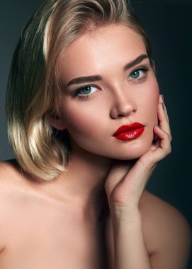 Stüdyoda gri arka planda güzel bir genç kadın var. Yakın plan portre. Saç stili.