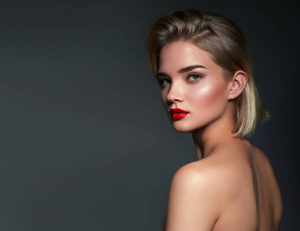 Beautiful young woman in studio on gray background. Close-up portrait. Hairstyle styling.