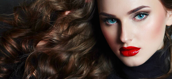 Модная девушка со стильной стрижкой надувает жвачку. Девушка в студии на синем фоне. Лицо девушки с ярким макияжем и желтым с черными тенями на глазах
.