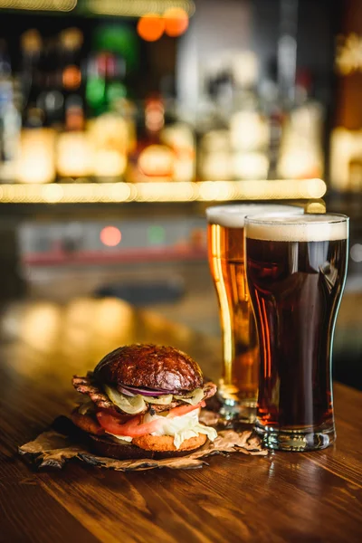 Hamburger et bière sombre sur fond de pub . — Photo