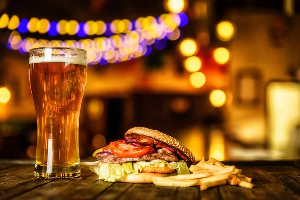 Hamburguesa y cerveza ligera sobre fondo de pub . — Foto de Stock