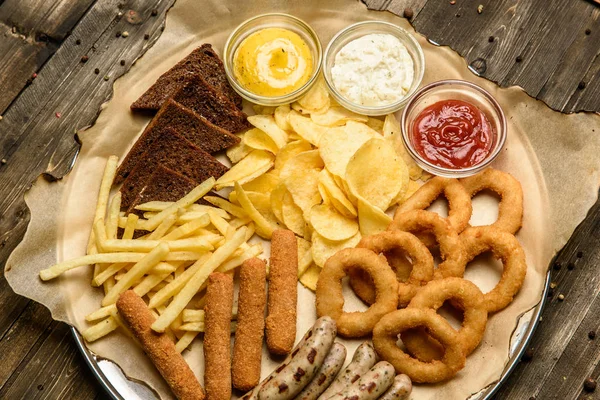 Brede selectie van snacks voor bier met verschillende sauzen op perkament bovenaanzicht — Stockfoto