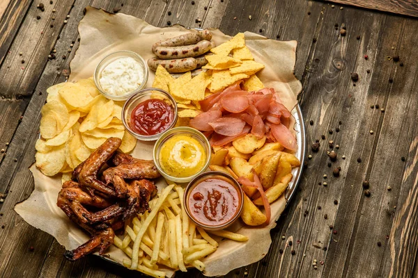 Brede selectie van snacks voor bier met verschillende sauzen op perkament bovenaanzicht — Stockfoto