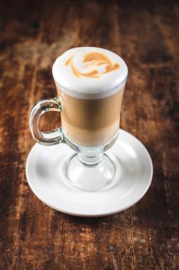 ahşap masa üzerinde bir yüksek cam ölçek latte