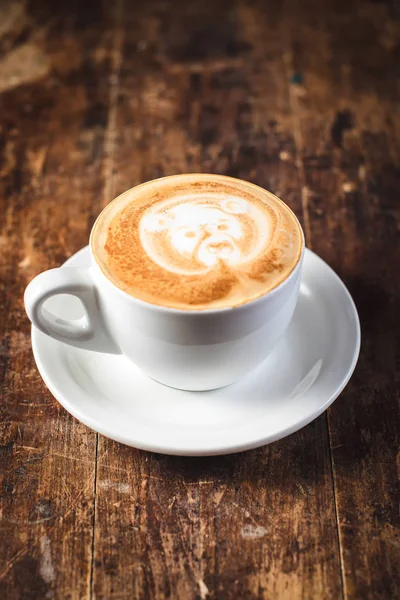 Tasse Kaffee mit Bärenmuster in weiß auf Holzgrund — Stockfoto