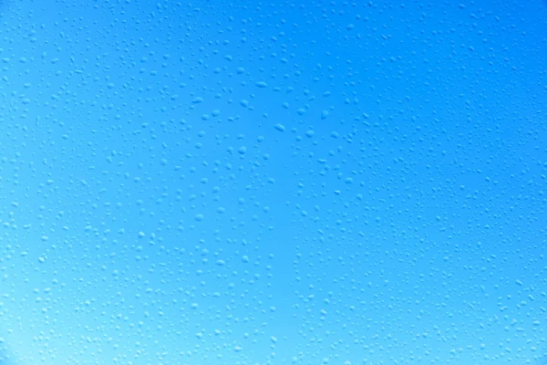Gotas de água em vidro com fundo azul céu — Fotografia de Stock
