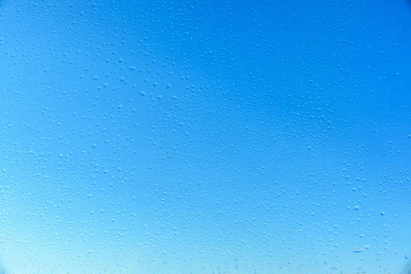 Gotas de água em vidro com fundo azul céu — Fotografia de Stock