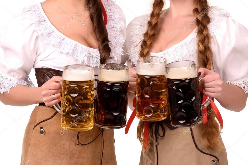 Two young sexy woman wearing a dirndl with beer mugs over white, Oktoberfest concept