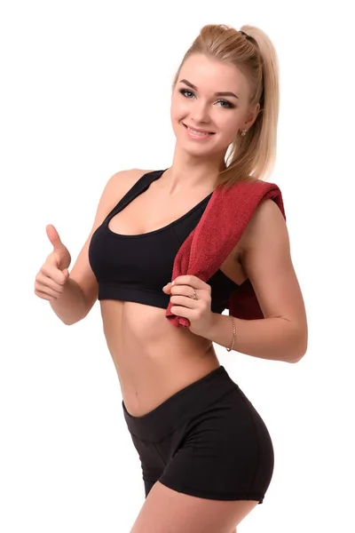 Hermosa y feliz chica atlética después de un entrenamiento, sosteniendo sobre los hombros la toalla roja pulgar encima del fondo blanco — Foto de Stock