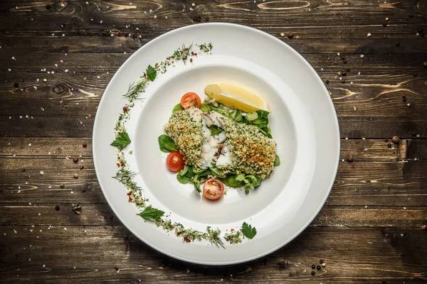 Filete de pescado con hierbas, limón, tomates cherry y especias sobre un fondo de madera plato blanco — Foto de Stock