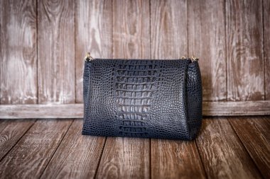 kahverengi ahşap zemin üzerinde mavi deri çanta.