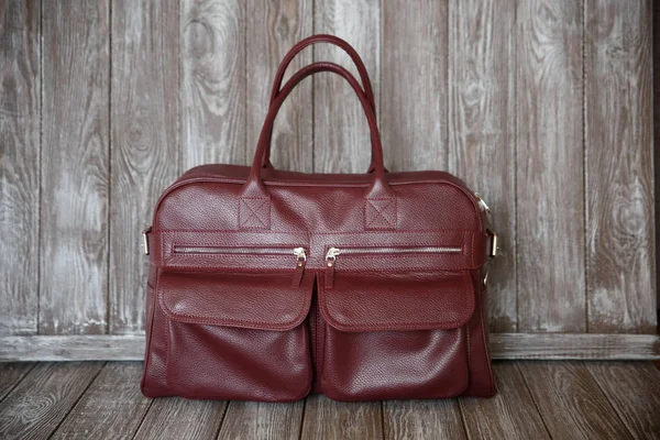 茶色の木製の背景に赤い革バッグ. — ストック写真