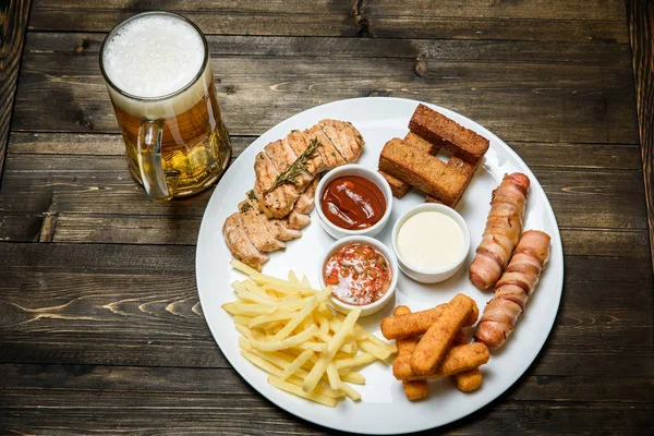 Cerveja em um copo em fundo de madeira. e lanche . — Fotografia de Stock