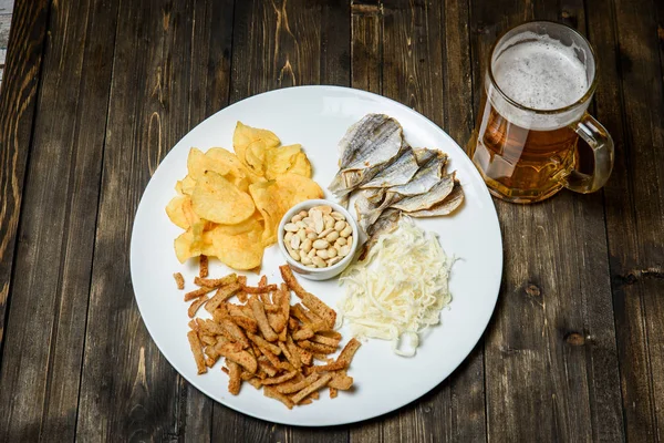 Ahşap arka plan üzerine bir bardak bira. ve snack. — Stok fotoğraf