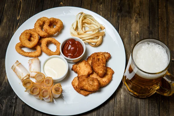 Cerveza en un vaso sobre fondo de madera. y merienda . — Foto de Stock