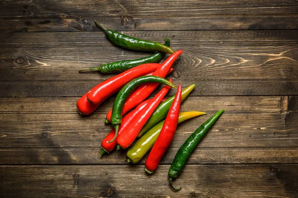 Červené a zelené chilli papričky na štítku na dřevěné pozadí — Stock fotografie