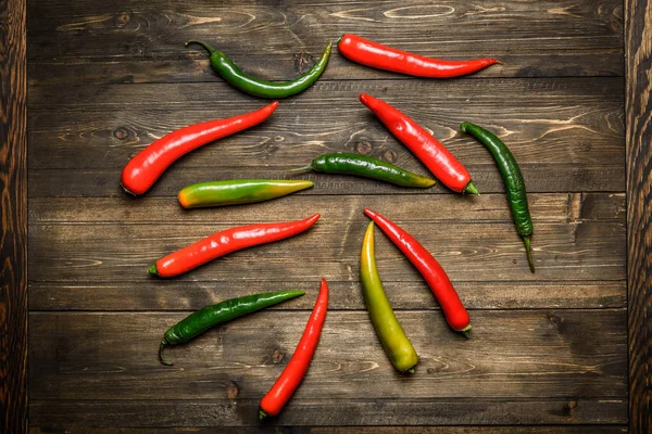 Červené a zelené chilli papričky na štítku na dřevěné pozadí — Stock fotografie