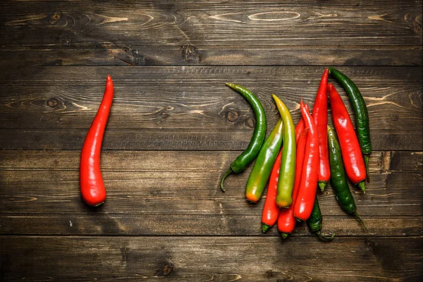 Červené a zelené chilli papričky na štítku na dřevěné pozadí — Stock fotografie