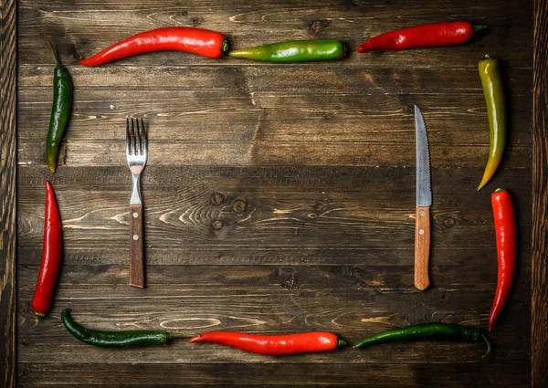 Red and green chili pepper on plate on wooden background