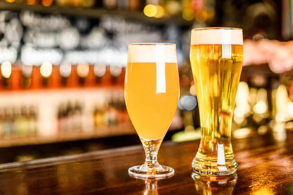 Un deux verre de bière légère sur un pub avec fond bokeh — Photo
