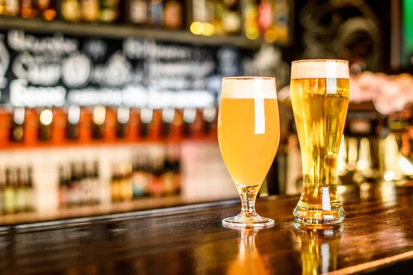 Un deux verre de bière légère sur un pub avec fond bokeh — Photo