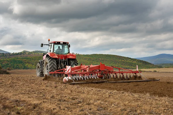 Farmář v traktoru připravuje půdu s kultivátorem seťového lůžka — Stock fotografie