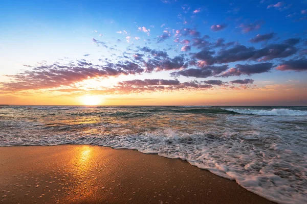 Bunte Meer Strand Sonnenaufgang mit tiefblauem Himmel und Sonnenstrahlen. — Stockfoto