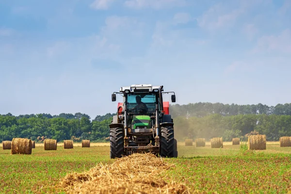 Tractor in a farmer field with balls of straw. — Stock Photo, Image