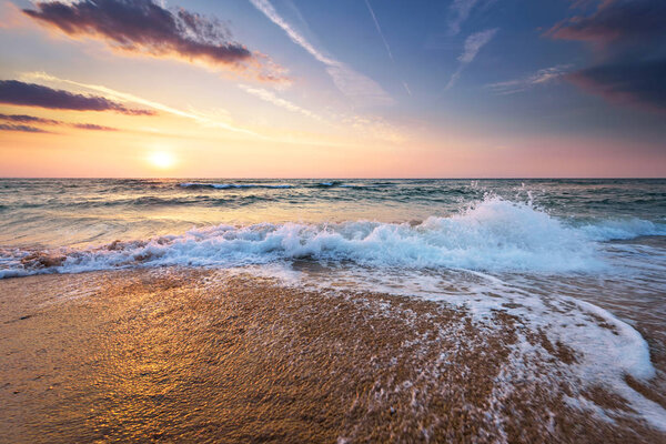 Colorful ocean beach sunrise with deep blue sky and sun rays.