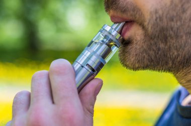Yetişkin adam parkta bir vape e-sigara sigara