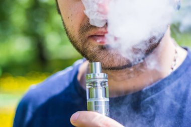Yetişkin adam parkta bir vape e-sigara sigara