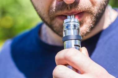 Yetişkin adam parkta bir vape e-sigara sigara