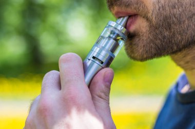 Yetişkin adam parkta bir vape e-sigara sigara
