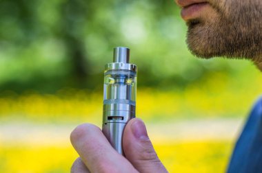 Yetişkin adam parkta bir vape e-sigara sigara