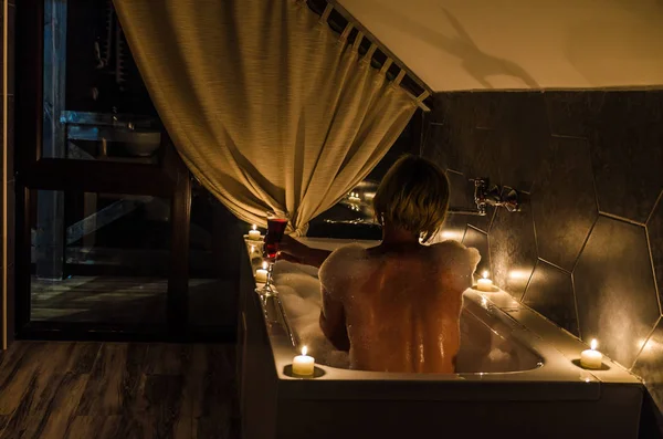 Genç kız banyoda mum ve şarap ile
