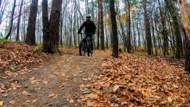 Sonbahar parkında bisiklet süren amatör bir binici.