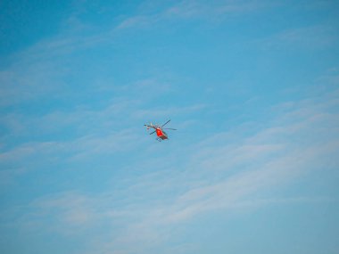 Mavi gökyüzündeki uzak kırmızı helikopter. Acil servis helikopter uçuşu. Metin yeri olan pankart şablonu. Sigorta ya da tıbbi destek konsepti. Güneşli mavi gökyüzü ve özel servis uçan aracı.