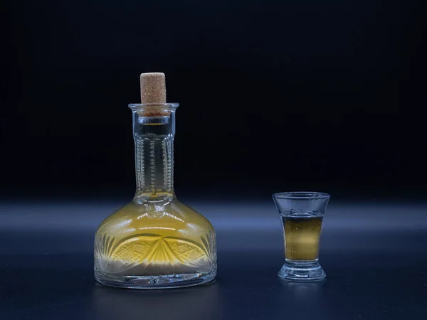 Ev yapımı votka ve koyu arka planda dolu bardak ile klasik sürahi. Alkolik içki hrenovuha şeffaf bir şarap şişesi içinde ve vurulmuş..