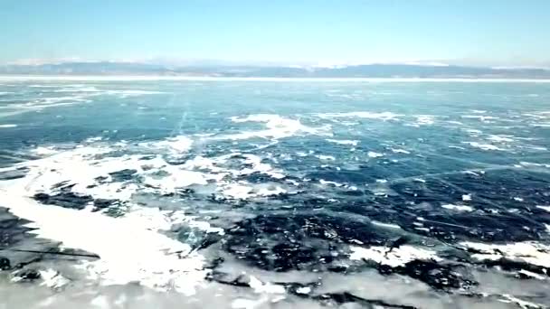 冬季空中俯瞰贝加尔湖全景 冰面上的蜘蛛网裂缝和蓝天下地平线上的远山 高瞻远瞩 — 图库视频影像