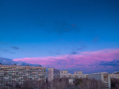 Şehir merkezindeki apartmanların üzerinde açık pembe bulutlar olan mavi gökyüzü. Sabah şehir manzarasının panoraması. Moskova şehri, Rusya.