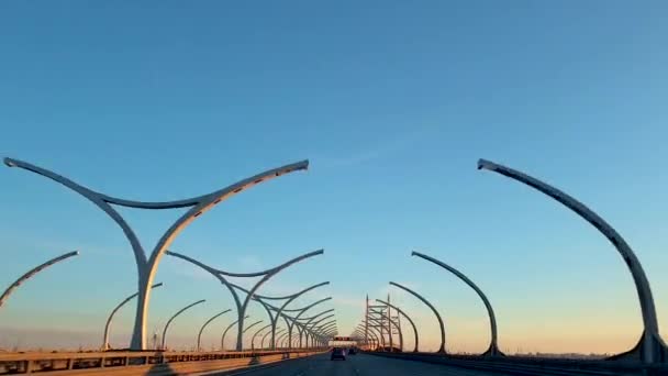 日落时 汽车在高速公路上行驶 有弧形灯柱塔的拱桥 圣彼得堡 俄罗斯 线性跟踪 — 图库视频影像