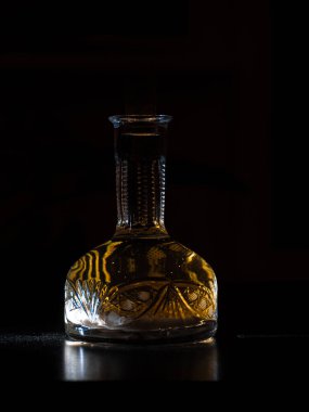 Koyu arkaplanda ev yapımı votka olan klasik sürahi. Alkolik, şeffaf şarap şişesinde hrenovuha içer. Dikey fotoğraf.
