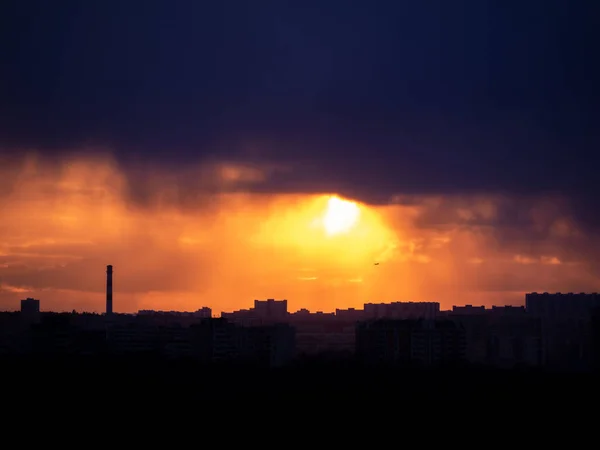 Colorful cloudy epic sky on sunset over the panoramic silhouette of the Moscow city skyline with far silhouette of the commercial jet