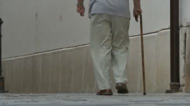 Yaşlı adam bastonla yürüyor.