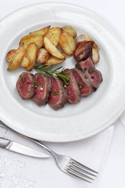 Dilim biftek ve patates kızartması bir plaka üzerinde