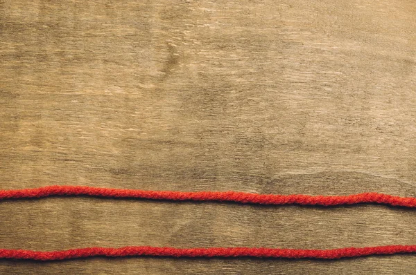 Zwei rote Fäden auf Holzgrund — Stockfoto