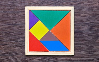 Tangram bulmacanın koyu ahşap arka plan üzerinde