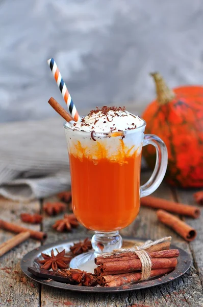 Smoothie à la citrouille avec cannelle et crème fouettée sur un fond en bois . — Photo