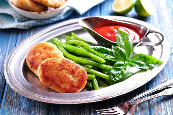 Вкусные рыбные торты с вареной зеленой фасолью и томатным соусом — стоковое фото