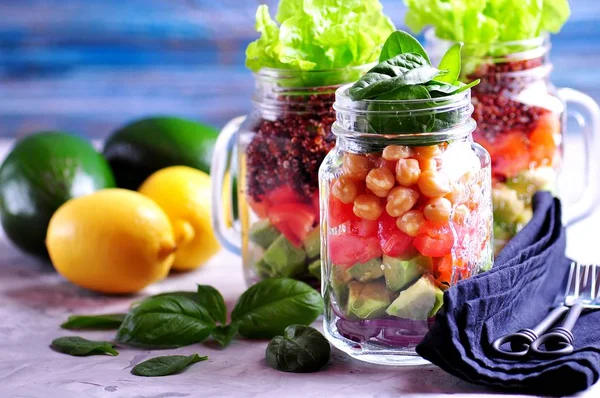 Gezonde salade met quinoa en kikkererwten, avocado, tomaat, rode ui, baby spinazie, sla, olijfolie in een Mason jars. — Stockfoto